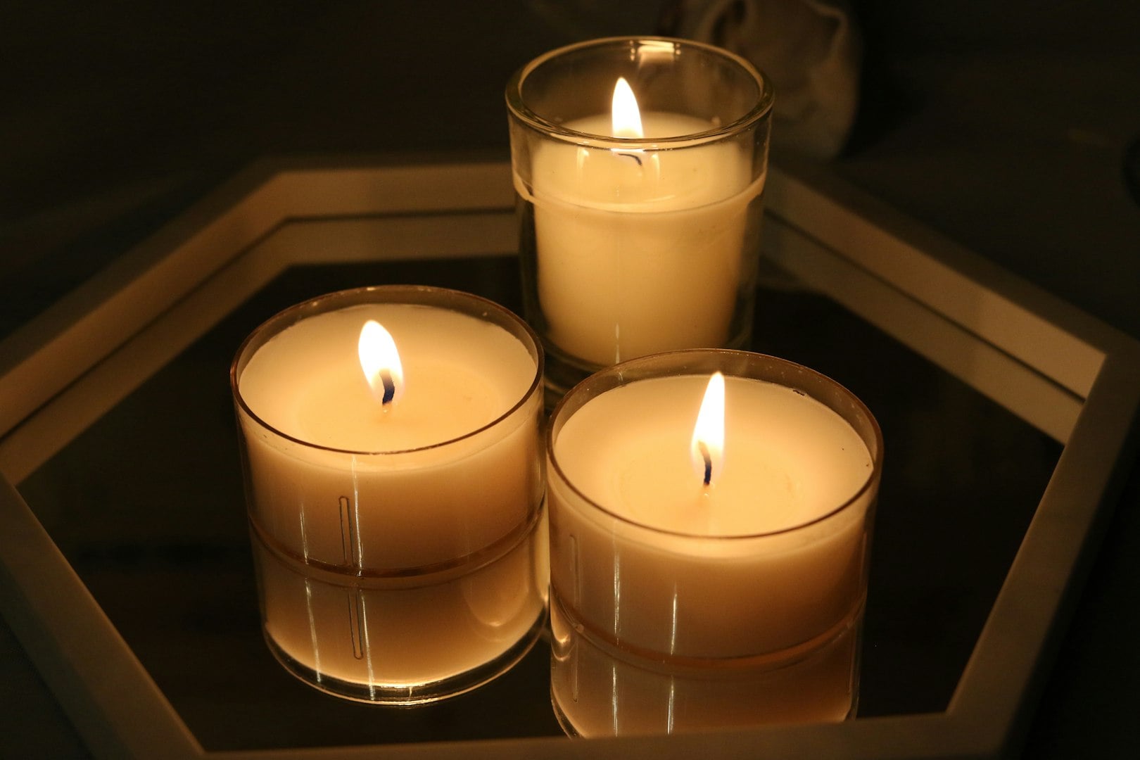 Concept of creative hobby and handmade candles. Close-up of female hands pouring melted soy wax into jar.